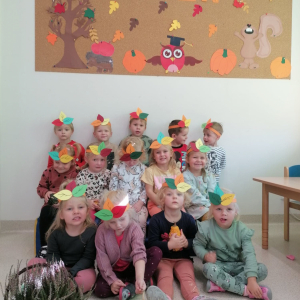 Grupa dzieci w jesiennych opaskach uśmiecha się do zdjęcia