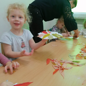 Dzieci wyklejają obrazki z kolorowych lisci