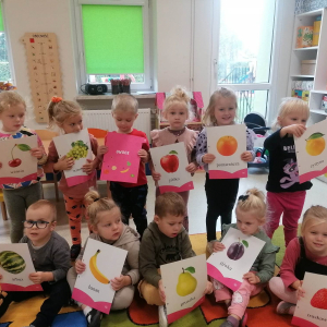 Dzieci trzymają w rękach plakaty z owocami i warzywami