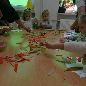 Dzieci wyklejają obraz z kolorowych lisci