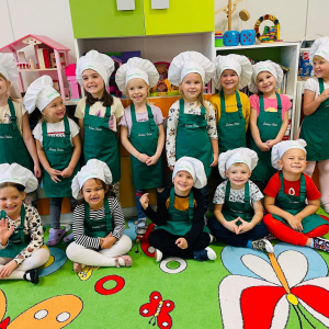 Dzieci pozują do zdjęcia grupowego w strojach kucharskich