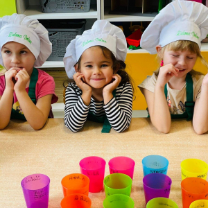 Dziewczynki w czapkach kucharskich czekają na soczek