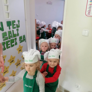 Dzieci w czapkach kucharskich idą do jadalni