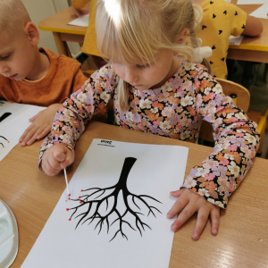 Dziewczynka maluje farbami jesienne drzewo