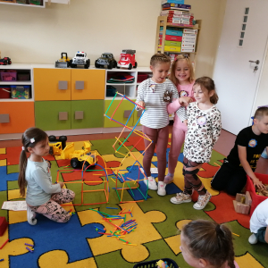 Dzieci budują konstrukcje na dywanie