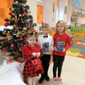 Dzieci stoją przy choince z prezentami