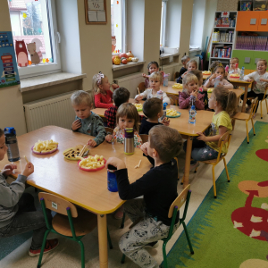 Dzieci siedzą przy stole i jedzą łakocie