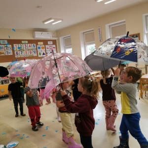 dzieci stoją pod parasolkami