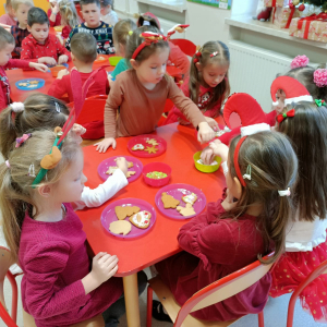 Dzieci przy stolikach dekorują pierniczki