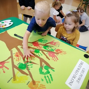 Zdjęcie przedstawia dzieci z grupy Żabki podczas tworzenia "Drzewka dłoni" 