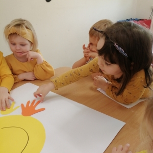 Na zdjęciu dzieci z grupy Biedronki wyklejają plakat z okazji Dnia Życzliwości