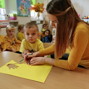 Na zdjęciu Wychowawca - Pani Justyna obrysowuje rączkę chlopcu z grupy Biedronki