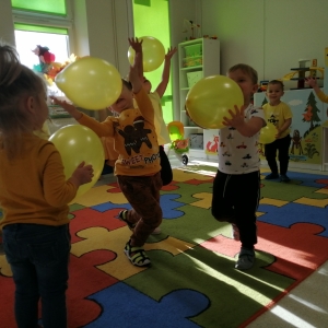 Na zdjęciu dzieci z grupy Biedronki, które bawią się w sali przedszkolnej i grają balonikiem, podbijają balon do góry