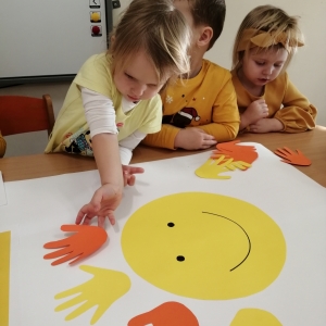 Na zdjęciu dzieci z grupy Biedronki wyklejają plakat z okazji Dnia Życzliwości