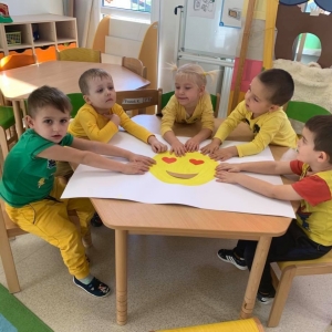 Na zdjęciu widać dzieci z grupy Myszki, które siedzą przy stoliku i wykonują wspólnie plakat z okazji Dnia życzliwości