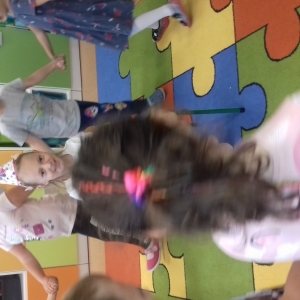 Dzieci tańczą na dywanie  w sali. Dziewczynka ma urodziny.