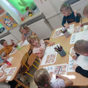 Dzieci z grupy Sarenki bawia się i uczą przy stoliku w sali przedszkolnej.