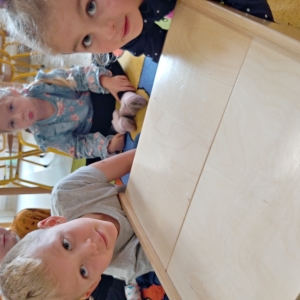 Dzieci z grupy Sarenki bawia się i uczą przy stoliku w sali przedszkolnej.