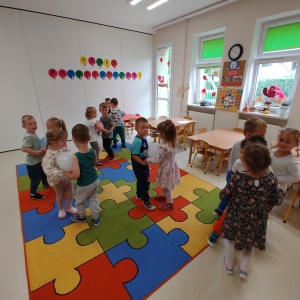 Dzieci tańczą na dywanie  w sali. Dzieci bawią się.