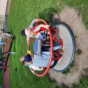 Dzieci bawią się na placu zabaw przy przedszkolu. Dzieci są radosne.