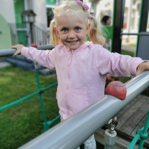 Na zdjęciu dziewczynka bawi się na placu zabaw. 