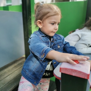 Na zdjęciu dziewczynka bawi się na placu zabaw. 