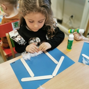 Dzieci robią pracę plastyczną z szopką bożonarodzeniową.